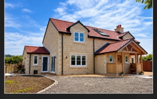 Completed bespoke stone home with red roof tiles and a covered entrance on the edge of the Cotswolds.